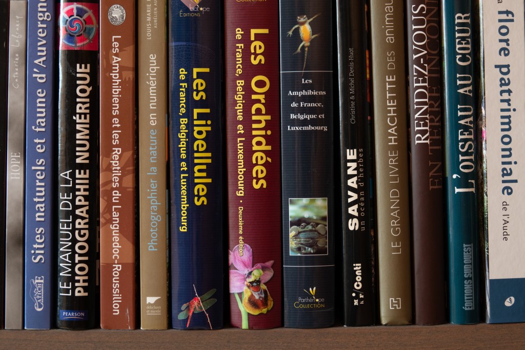 Une étagère remplie de livres sur la nature, y compris des ouvrages sur les amphibiens, les libellules et la photographie numérique.
