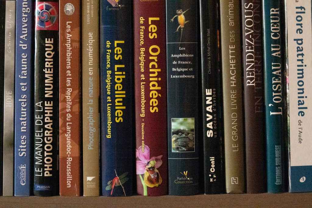 Une étagère remplie de livres sur la nature, la photographie et les animaux, avec des titres en français tels que 'Les Amphibiens', 'Les Libellules' et 'L'Oiseau au cœur'.