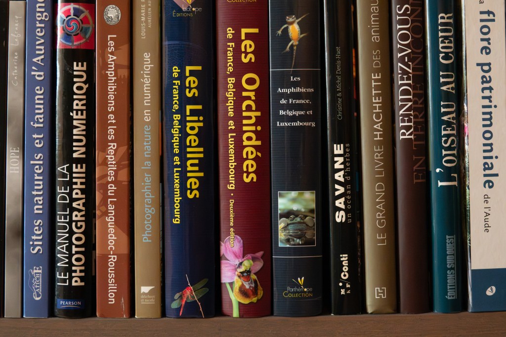 Une étagère remplie de livres sur la nature et la faune, avec des titres concernant les amphibiens, les libellules et la photographie numérique.